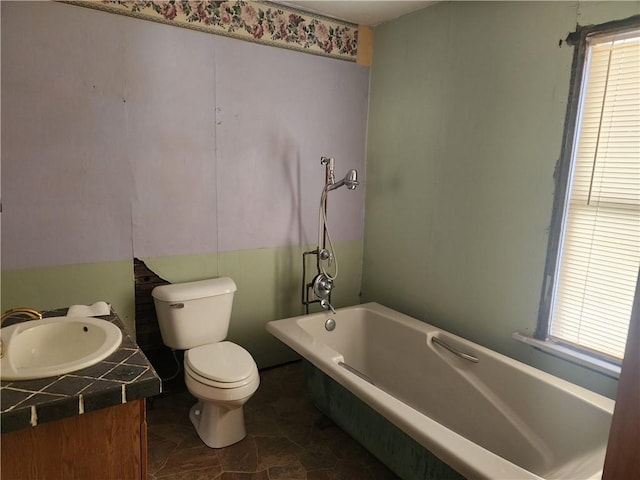 bathroom featuring a washtub, vanity, and toilet