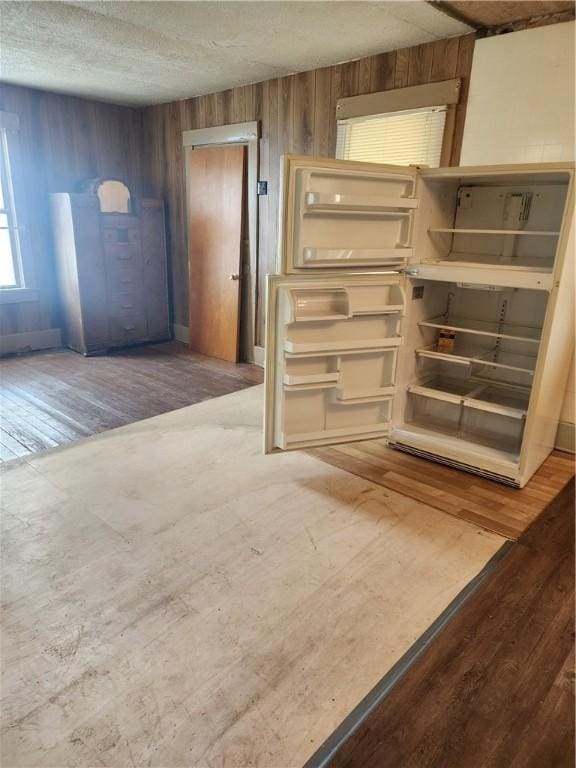 interior space featuring a textured ceiling, wood walls, and wood finished floors