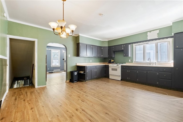 kitchen featuring hanging light fixtures, white range, light hardwood / wood-style flooring, and a wealth of natural light