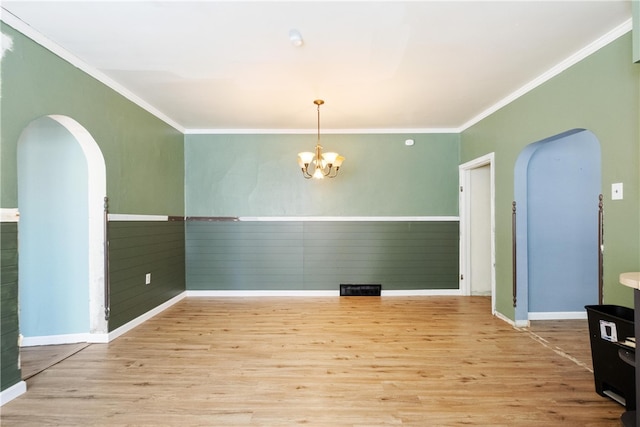 unfurnished room featuring ornamental molding, light wood-type flooring, and a notable chandelier