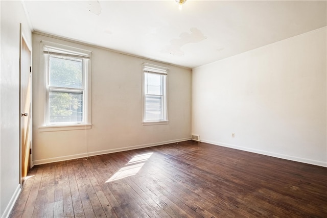 empty room with dark hardwood / wood-style flooring, plenty of natural light, and ornamental molding