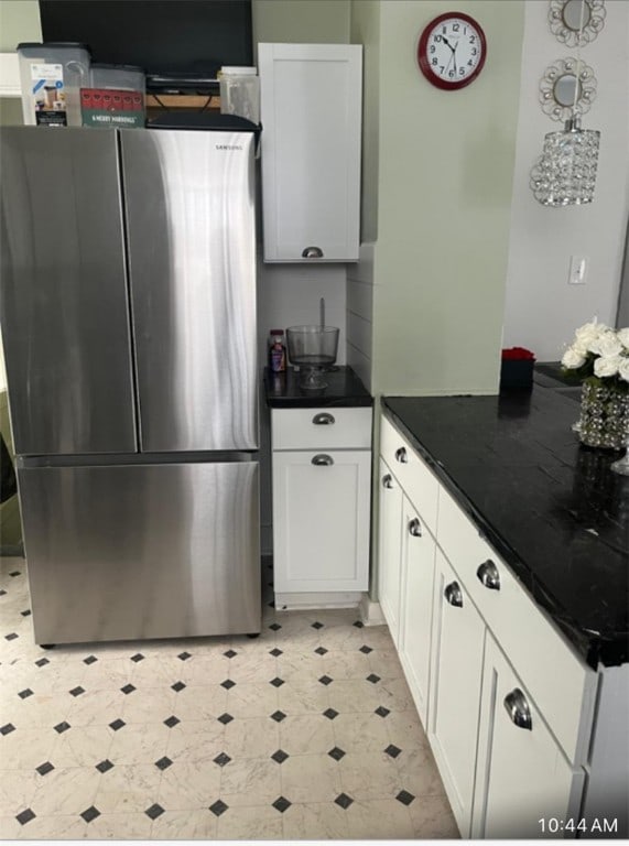 kitchen with stainless steel refrigerator, decorative light fixtures, and white cabinets