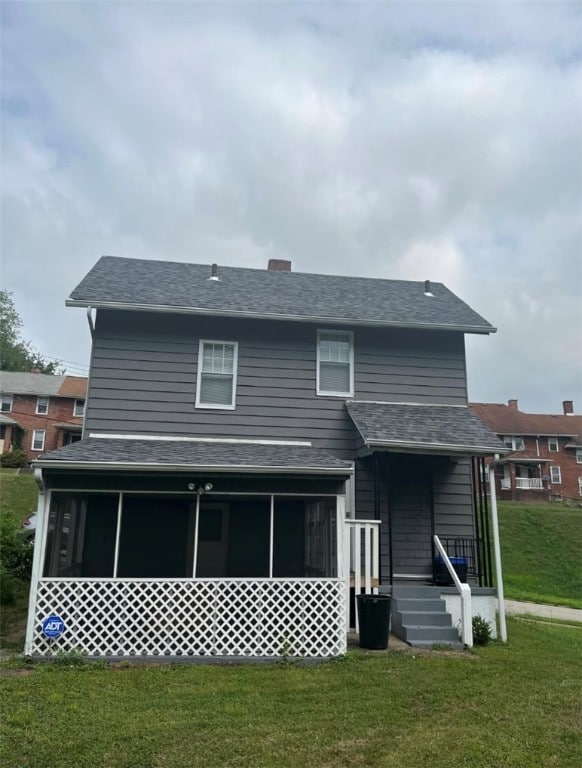 rear view of house with a lawn and a sunroom