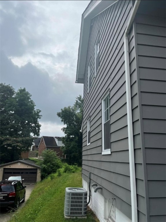 view of side of home with an outdoor structure, a garage, and central air condition unit