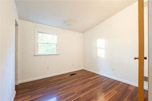 spare room with lofted ceiling and dark wood-type flooring