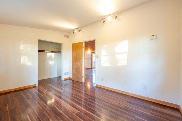 unfurnished bedroom with dark wood-type flooring, a closet, and lofted ceiling