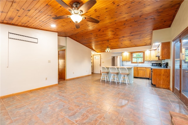 kitchen featuring ceiling fan, appliances with stainless steel finishes, wooden ceiling, and a kitchen breakfast bar