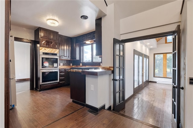 kitchen featuring backsplash, dark hardwood / wood-style flooring, french doors, dark brown cabinetry, and double oven