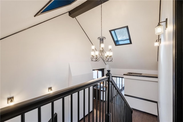 stairs featuring wood-type flooring, beamed ceiling, a skylight, and plenty of natural light