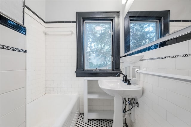 bathroom featuring tile walls, tile patterned flooring, and a washtub