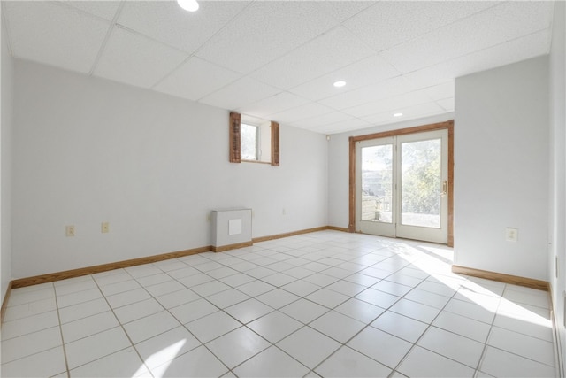 unfurnished room with a drop ceiling and light tile patterned floors