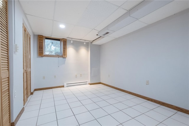 interior space with light tile patterned floors, a baseboard radiator, and a drop ceiling