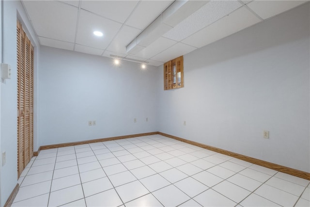 empty room with a paneled ceiling and light tile patterned floors