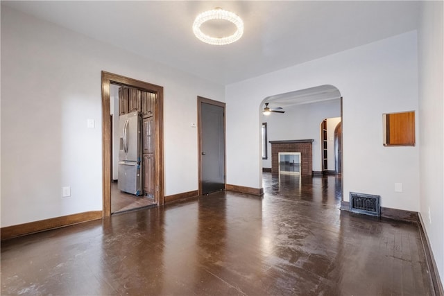 spare room featuring ceiling fan and a brick fireplace