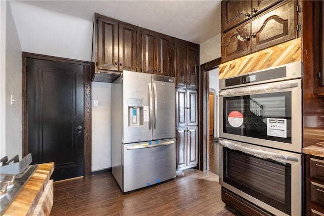 kitchen featuring dark wood-type flooring, butcher block counters, appliances with stainless steel finishes, and dark brown cabinetry