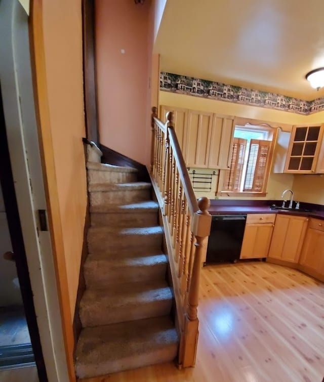 staircase with hardwood / wood-style floors and sink