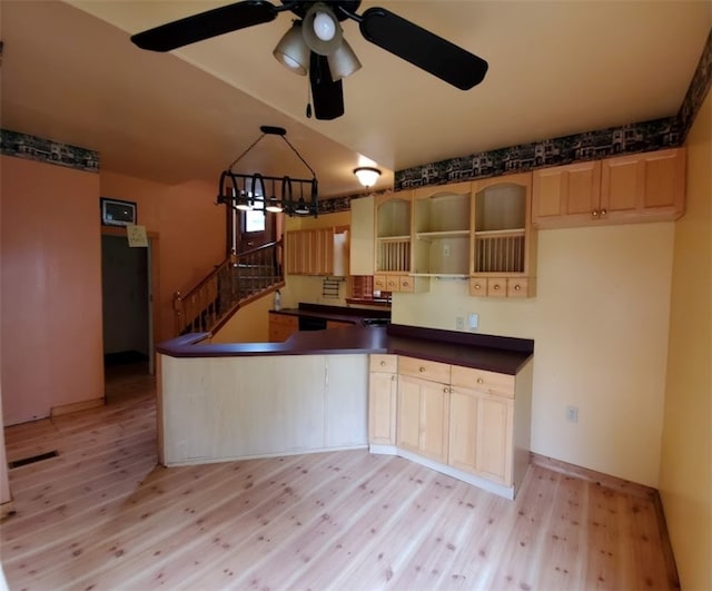 kitchen with light wood-type flooring, ceiling fan with notable chandelier, kitchen peninsula, and light brown cabinets