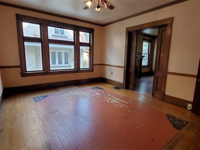 spare room with wood-type flooring, crown molding, ceiling fan, and a wealth of natural light