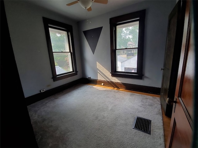 carpeted empty room featuring ceiling fan and a healthy amount of sunlight