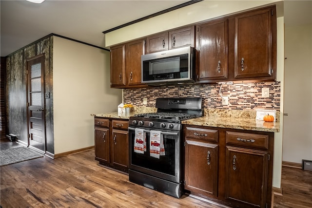 kitchen featuring dark brown cabinetry, wood-type flooring, stainless steel appliances, light stone countertops, and crown molding