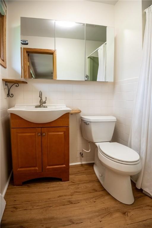 bathroom with wood-type flooring, vanity, tile walls, and toilet