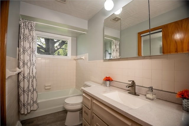 full bathroom featuring vanity, shower / bath combo, hardwood / wood-style flooring, tile walls, and toilet