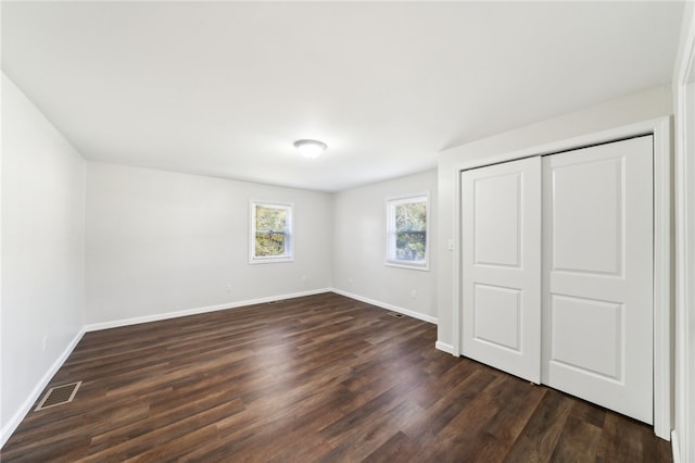 unfurnished bedroom featuring a closet and dark wood-type flooring