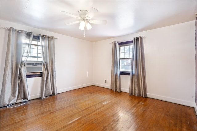 empty room with ceiling fan, cooling unit, hardwood / wood-style floors, and a healthy amount of sunlight