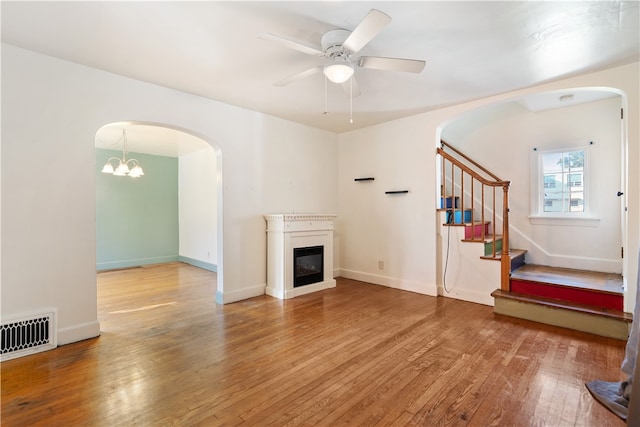 unfurnished living room with wood-type flooring and ceiling fan with notable chandelier