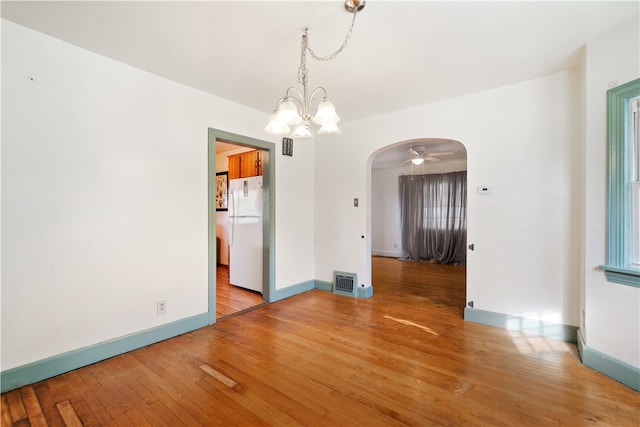 unfurnished dining area with hardwood / wood-style flooring and ceiling fan with notable chandelier