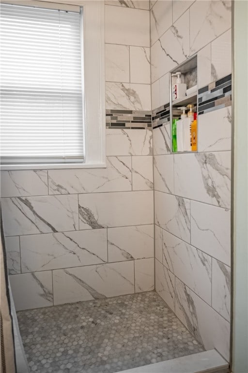 bathroom featuring a tile shower and a wealth of natural light