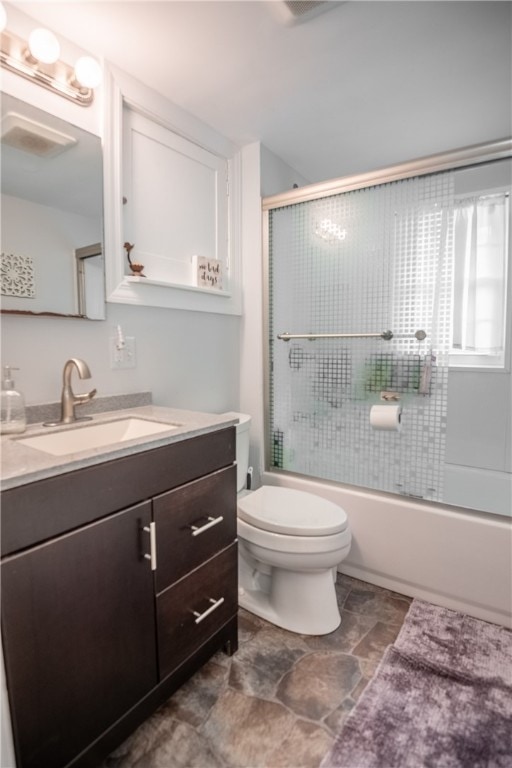 full bathroom with bath / shower combo with glass door, vanity, and toilet