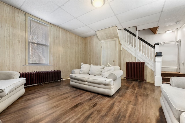 living room featuring dark hardwood / wood-style floors, radiator heating unit, and a paneled ceiling