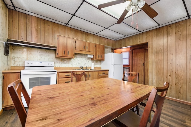 kitchen featuring a paneled ceiling, white appliances, wooden walls, and dark hardwood / wood-style floors