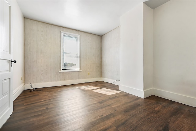 spare room with wooden walls and dark wood-type flooring