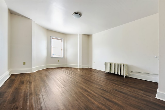 unfurnished room with radiator and dark wood-type flooring