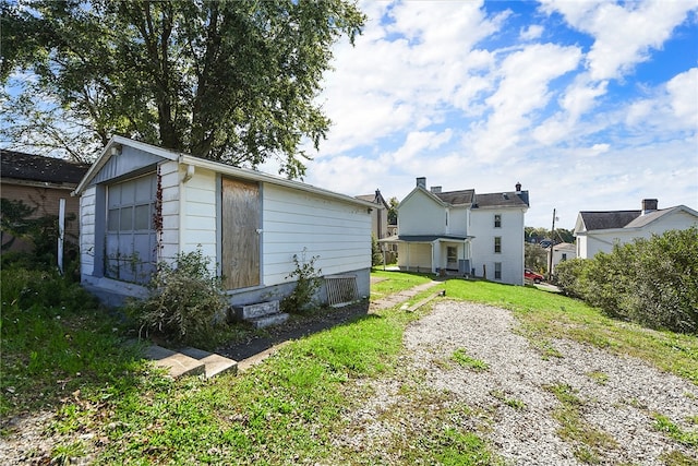 rear view of house featuring an outdoor structure and a lawn