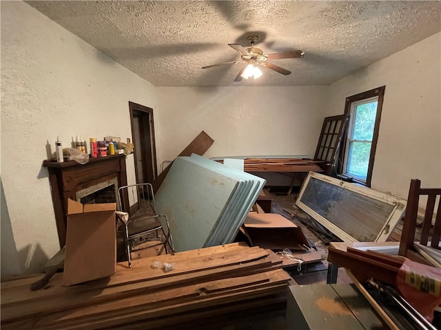 miscellaneous room featuring a textured ceiling, a fireplace, and ceiling fan