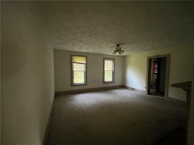 carpeted spare room featuring ceiling fan and a textured ceiling