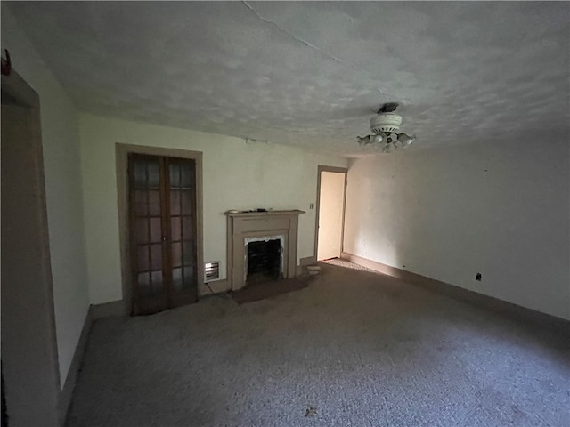 unfurnished living room with ceiling fan, carpet floors, and a textured ceiling