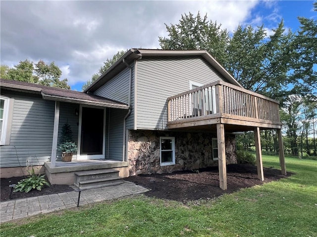 rear view of property with a yard, a wooden deck, and stone siding