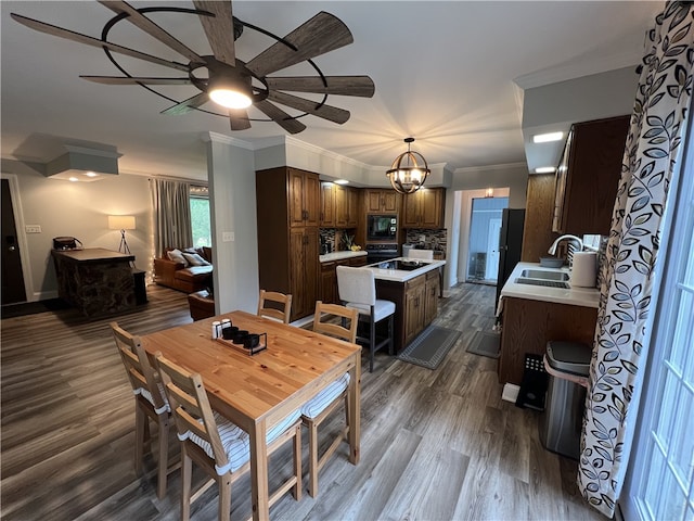 dining space featuring ornamental molding, sink, dark wood-type flooring, and ceiling fan with notable chandelier