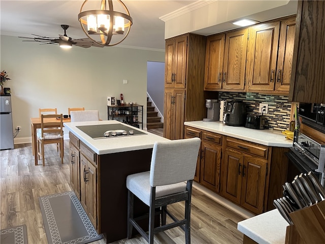 kitchen featuring a kitchen island, black electric cooktop, stainless steel fridge, crown molding, and decorative backsplash