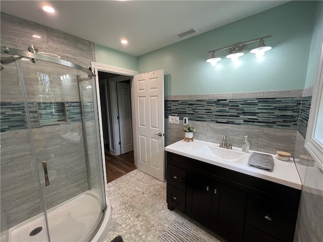 bathroom with tile walls, vanity, hardwood / wood-style floors, and walk in shower