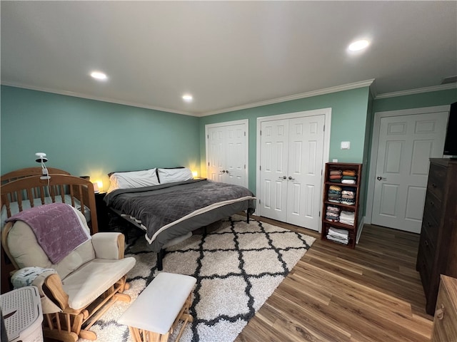 bedroom featuring ornamental molding, multiple closets, and hardwood / wood-style flooring