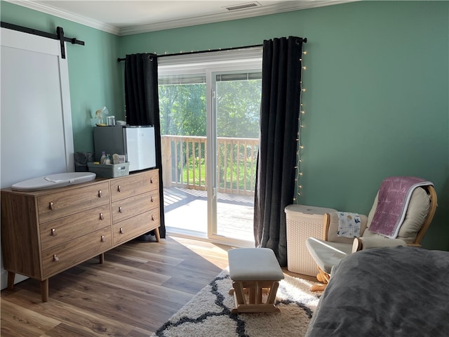 bedroom with a barn door, refrigerator, access to exterior, crown molding, and hardwood / wood-style flooring