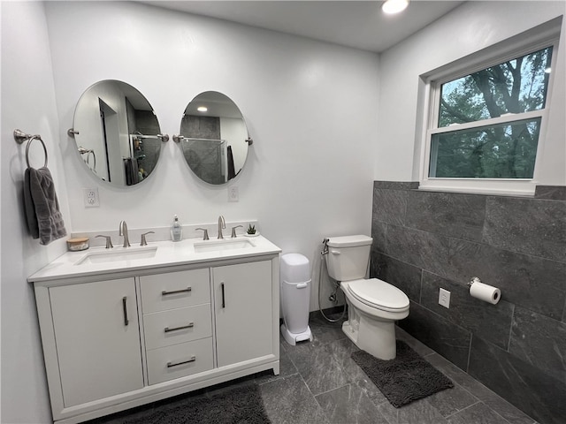 bathroom with toilet, vanity, and tile walls