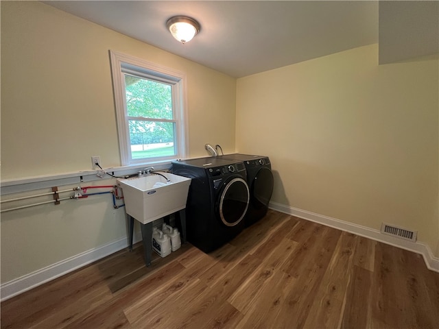 laundry room with washing machine and dryer, sink, and dark hardwood / wood-style floors