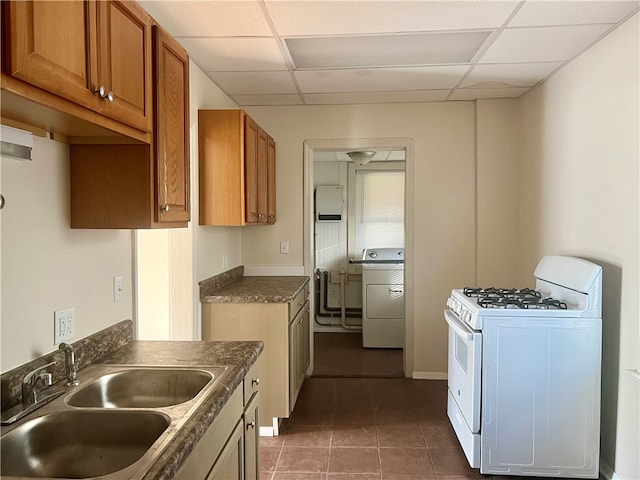 kitchen featuring white gas range, a drop ceiling, sink, and washer / dryer