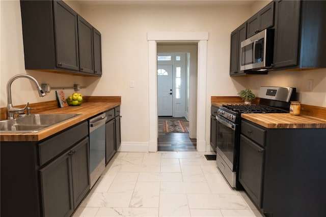 kitchen featuring appliances with stainless steel finishes, sink, and wood counters